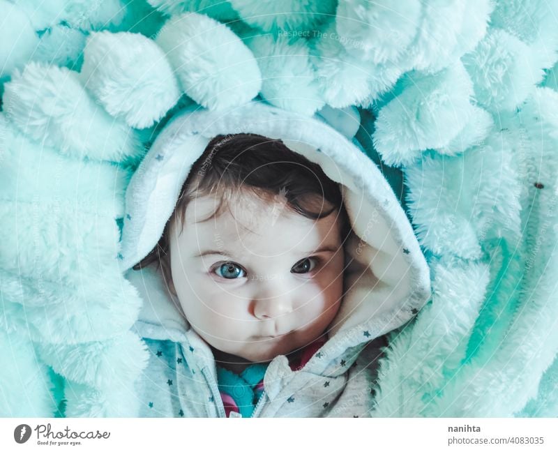 Kleines Baby eingewickelt mit einer warmen grünen Decke Porträt kleines Mädchen künstlerisch Winter gemütlich Vorleger warme Kleidung heimwärts blaue Augen