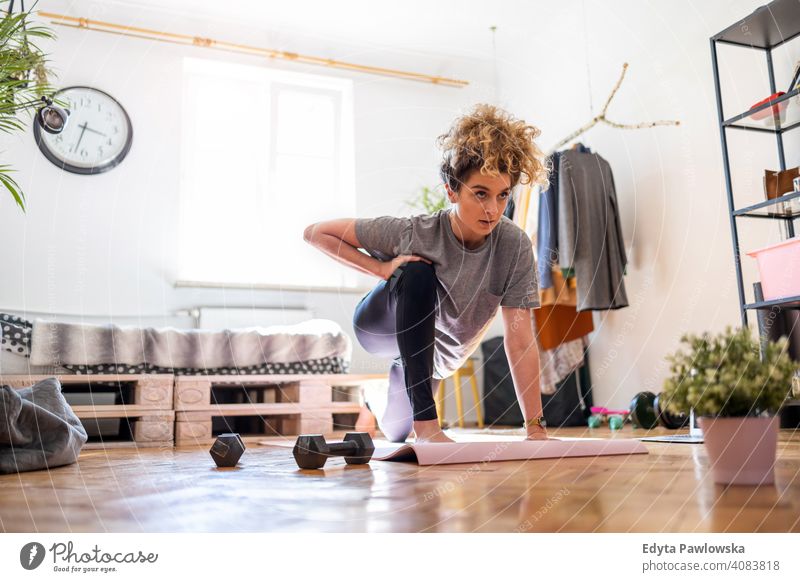 Junge Frau macht Fitness-Übung zu Hause Gerät Training Trainingsmatte Fitnessstudio passen Spaß Sport Gesundheit Stock Yoga aktiv Glück Lächeln heiter