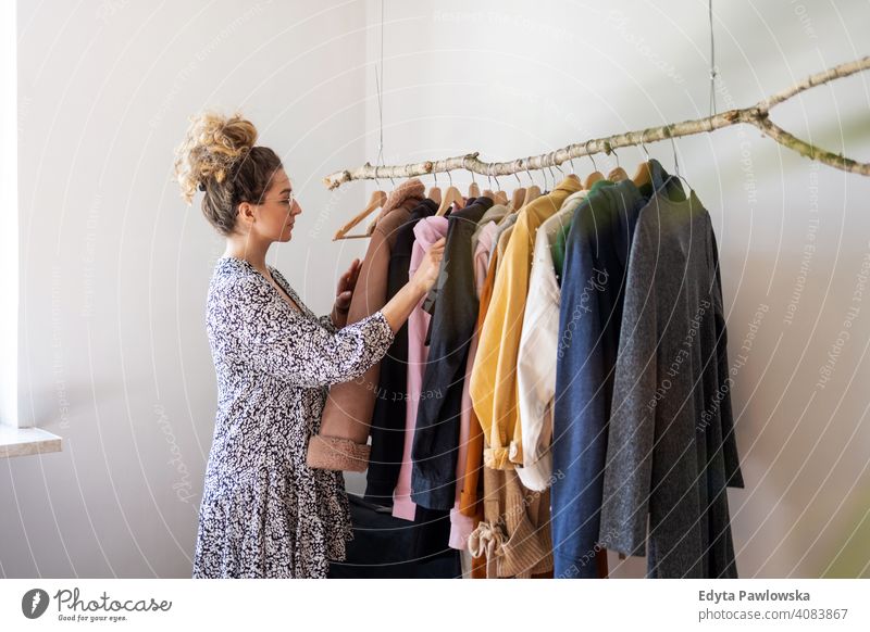 Junge Frau beim Einkaufen in einer Kleiderboutique Mode Bekleidung Kleidung modisch Ablage auserwählend Einzelhandel Laden Werkstatt Sale Kleiderbügel Kunde