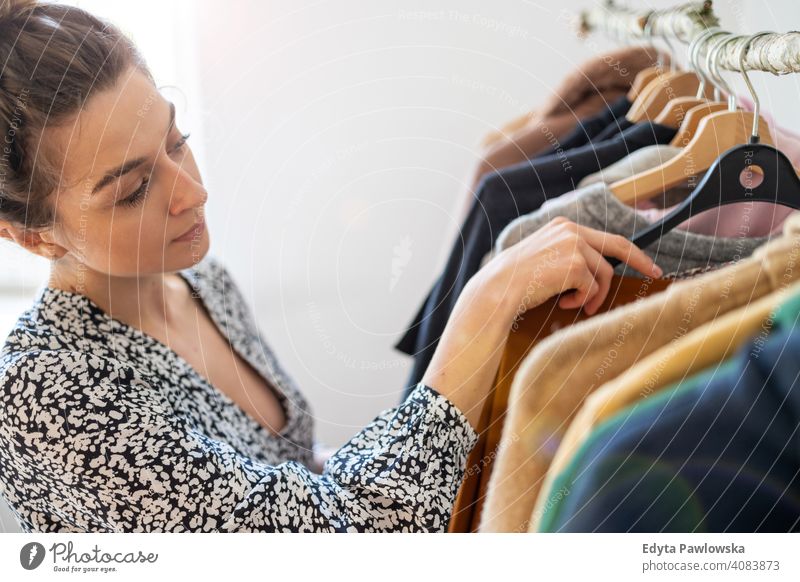 Junge Frau beim Einkaufen in einer Kleiderboutique Mode Bekleidung Kleidung modisch Ablage auserwählend Einzelhandel Laden Werkstatt Sale Kleiderbügel Kunde