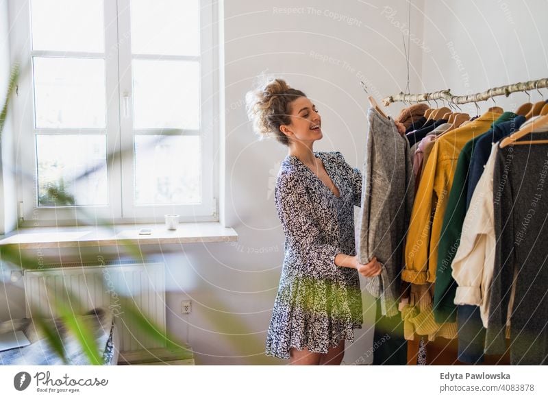 Junge Frau wählt Kleidung Mode Bekleidung modisch Ablage auserwählend Einzelhandel Laden Werkstatt Sale Kleiderbügel Kunde Stil Käufer konsumgeil Kleiderschrank