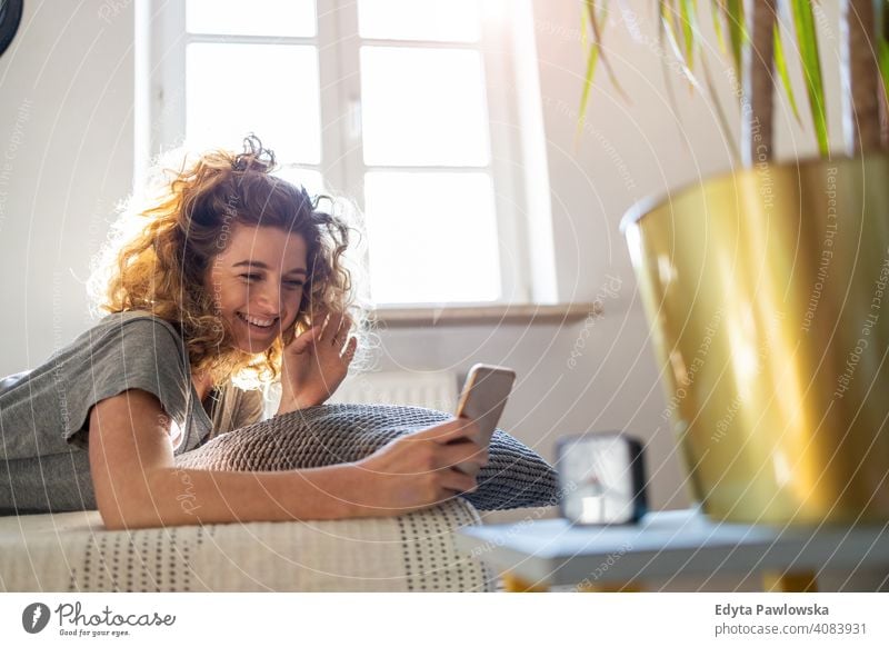 Junge Frau benutzt Smartphone im Bett Morgen Uhr aussruhen Erholung schlafen wach Wecker schläfrig Aufwachen Appartement Freizeit Schlafzimmer Haus heimwärts