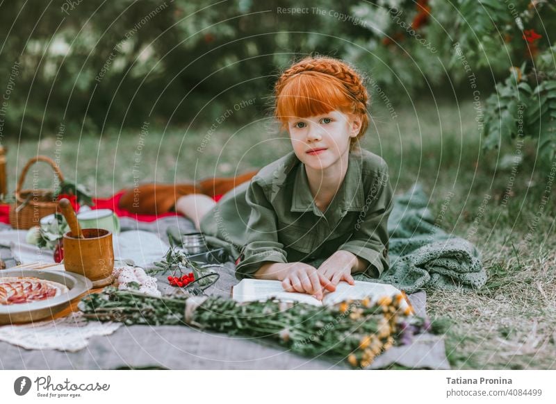 Rothaarige kleine Mädchen lesen Buch bei Retro-Picknick im Freien altehrwürdig retro Frisur Kleid Etage Geschichte lernen positiv Garten hübsch Decke Kleinkind