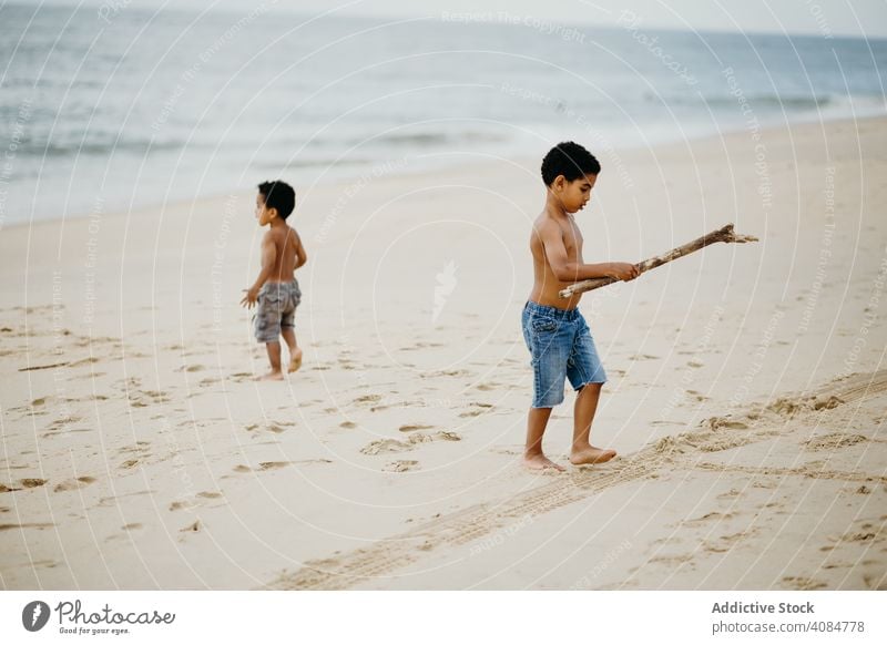 Schwarze Jungen spielen am Strand Brüder MEER Spielen Stöcke Spaß Zusammensein Sommer Wasser ohne Hemd Barfuß Kinder Geschwister Glück Wochenende Lifestyle