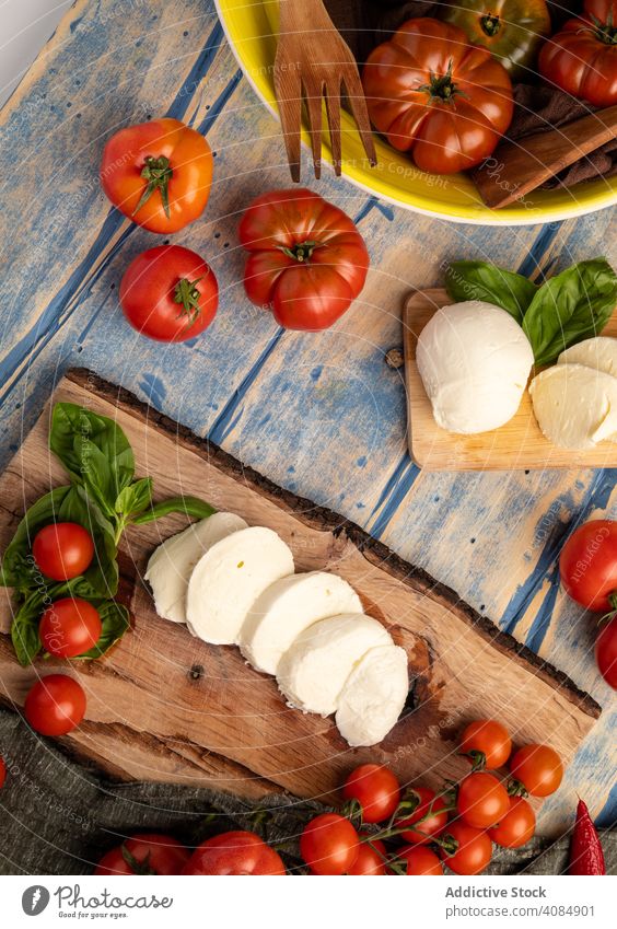 Salatzutaten auf Brett und Serviette Tomaten Käse Basilikum Holzplatte Salatbeilage Mozzarella Blätter frisch reif Zutaten Lebensmittel Mahlzeit Küche