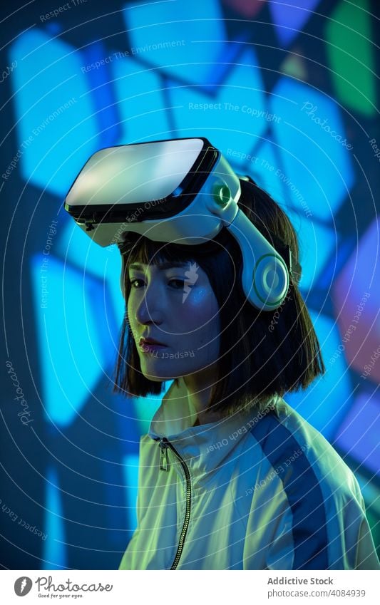 Frau im VR-Headset virtuell Realität Technik & Technologie neonfarbig Licht berührend Gerät digital Innovation jung Person Brille asiatisch modern Entertainment