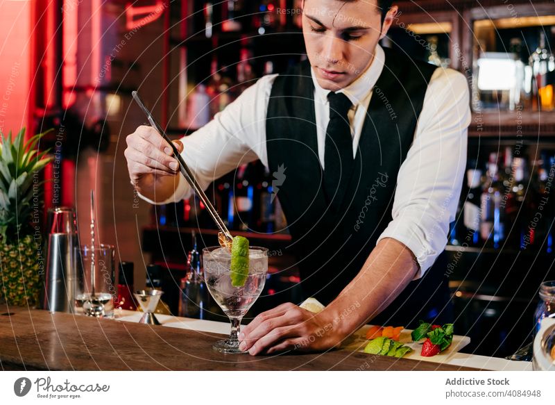 Barkeeper bei der Zubereitung von Getränken Barmann Mann Ananas Glas Kaukasier Gießen Cocktail Krawatte elegant Feier Schüttler Gastfreundschaft Reichtum