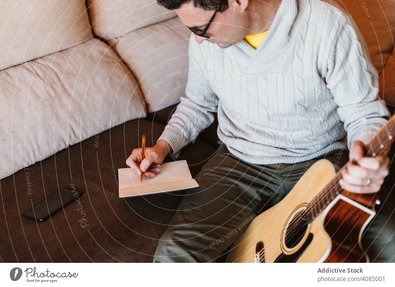 Musiker schreibt in ein Notizbuch Gitarre Notebook schreibend akustisch Schüler Appartement Bleistift heimwärts Mann Hand Raum jung spielen Entertainment Typ