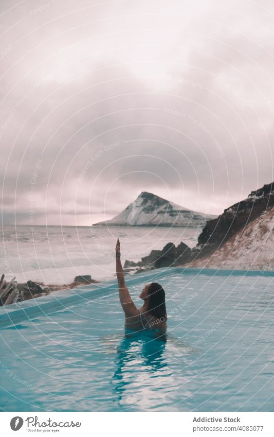 Frau im Pool in der Nähe von Meer und Hügeln am Ufer MEER Klippe jung Hand Seite Wasser aussruhen Küste Felsen Himmel stürmisch wolkig Sommer Erholung