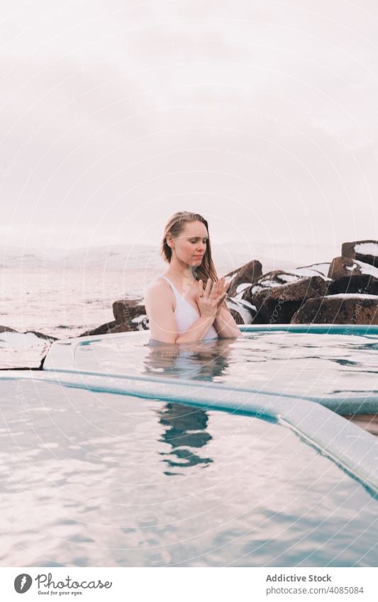 Frau sitzt im Pool in der Nähe von Steinen jung aussruhen Wasser geschlossene Augen Felsen Himmel wolkig Sommer Körper Erholung Gesundheit Natur Freizeit