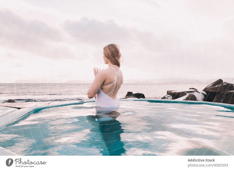 Frau sitzt im Pool in der Nähe von Steinen jung aussruhen Wasser geschlossene Augen Felsen Himmel wolkig Sommer Körper Erholung Gesundheit Natur Freizeit