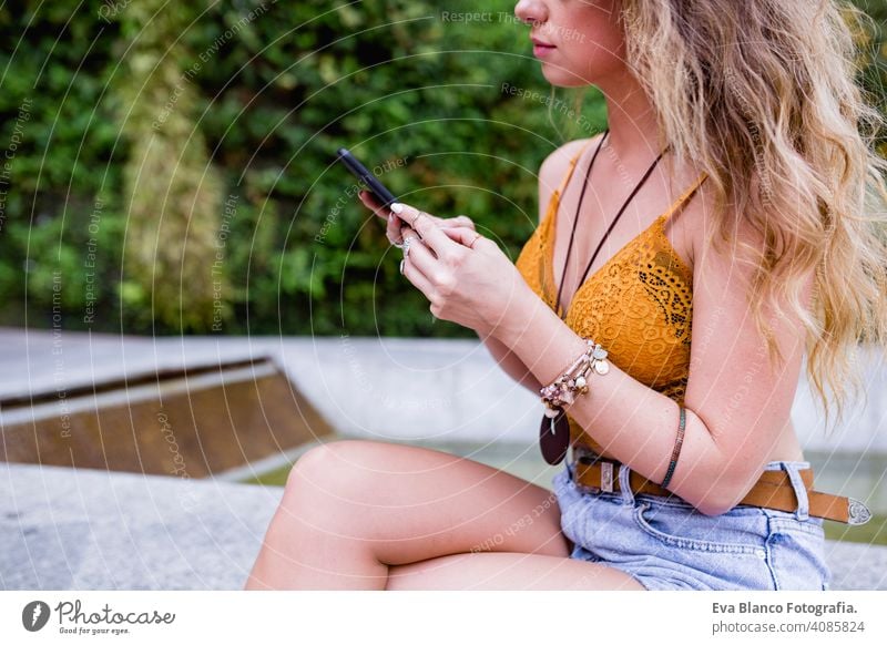 junge blonde schöne Frau auf der Straße mit Handy und lächelnd. Lifestyle im Freien. Sommerzeit, grüner Hintergrund klug urban Glück Menschen Lächeln laufen