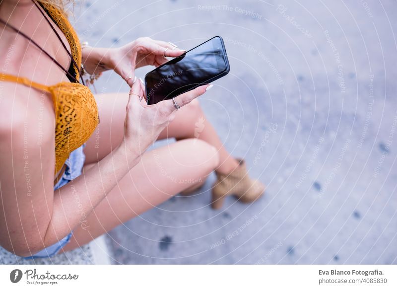 junge blonde schöne Frau auf der Straße mit Handy und lächelnd. Lifestyle im Freien. Sommerzeit, grüner Hintergrund klug urban Glück Menschen Lächeln laufen