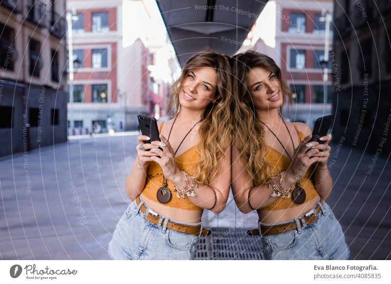 junge blonde schöne Frau auf der Straße mit Handy. Glas-Reflexion. Lifestyle im Freien. Sommerzeit. klug Anruf urban Glück Menschen Lächeln laufen modern spät