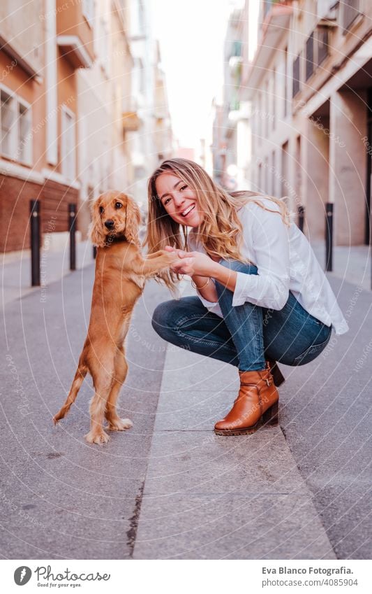 Junge Frau auf der Straße, die ihren süßen Cocker-Hund umarmt. Lifestyle im Freien mit Haustieren laufen Großstadt urban Reinrassig Kaukasier Schürhaken