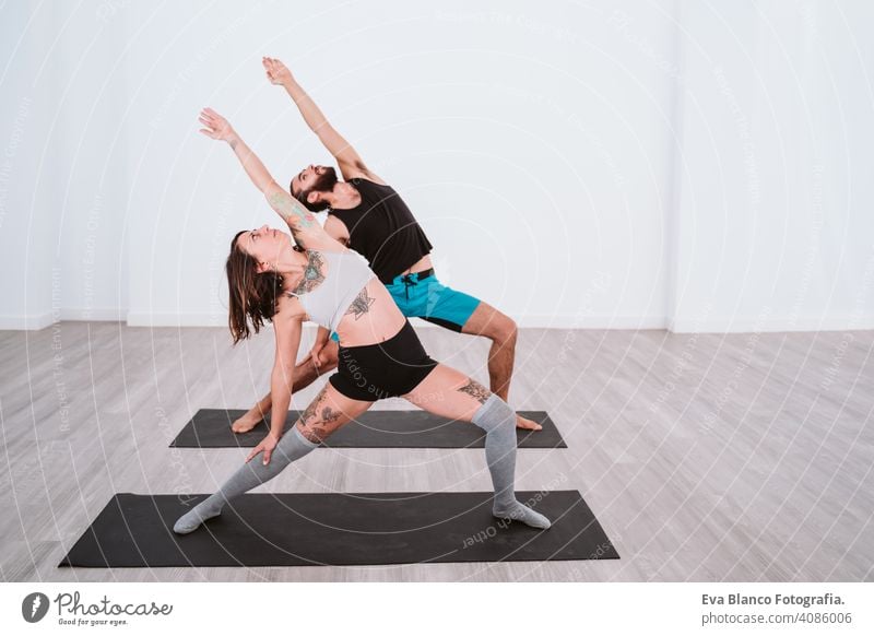 junger Mann und Frau üben Yoga-Sport in der Turnhalle. Gesunder Lebensstil Junge Gesundheit Lifestyle im Innenbereich Fitnessstudio Atelier weiß hispanisch