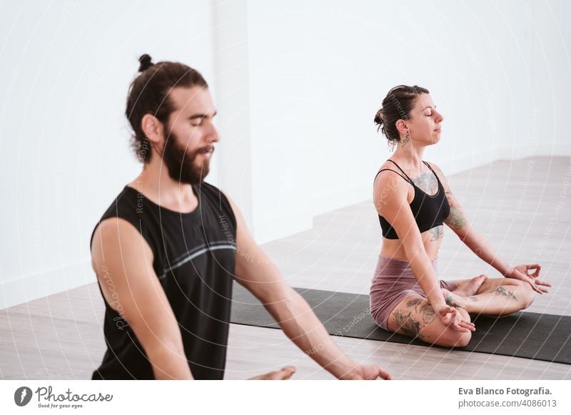 junger Mann und Frau üben Yoga-Sport in der Turnhalle. Gesunder Lebensstil Junge Gesundheit Lifestyle im Innenbereich Fitnessstudio Atelier weiß hispanisch