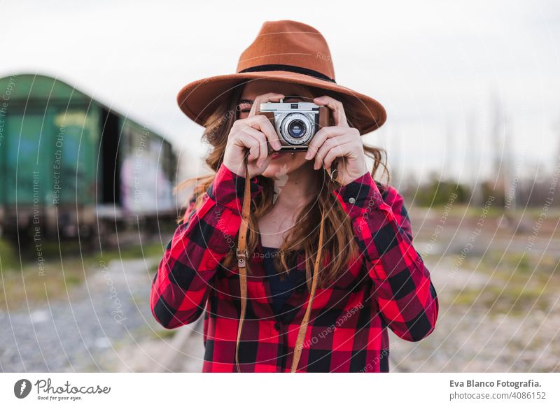 junge schöne Frau trägt lässige Kleidung und einen Hipster-Hut, der ein Bild mit einer Vintage-Kamera macht. Draußen Stadt Hintergrund. Lebensstil. Glück