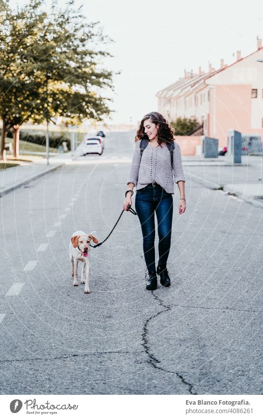 Junge Frau und ihr Hund im Freien, die an der Straße spazieren gehen. Herbstzeit Park jung Liebe Haustier Besitzer sonnig schön Glück Lächeln gemischte Rasse