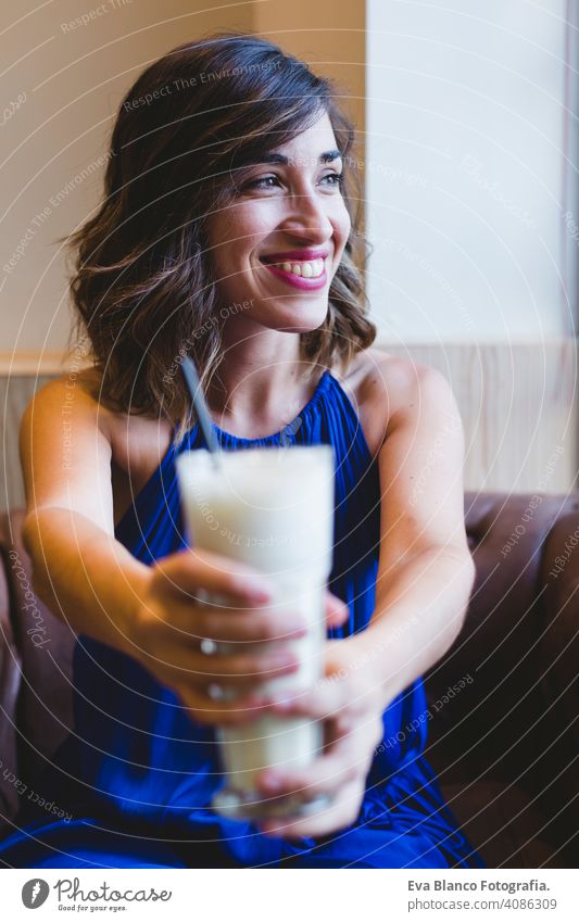 junge schöne Frau genießt ein Smoothie-Getränk in einem Cafe. Lässiges blaues Kleid. Modernes Leben in Innenräumen. selektiver Fokus benutzend im Innenbereich