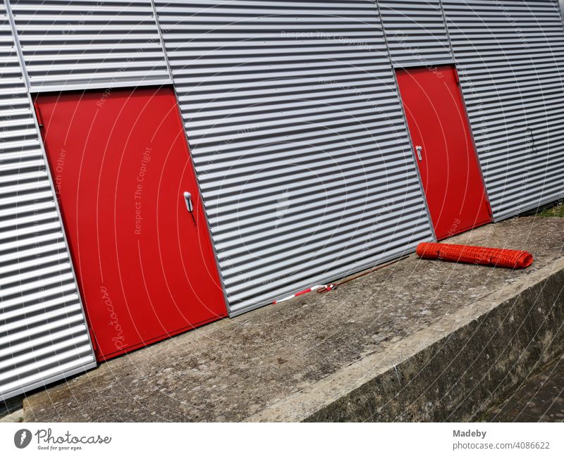 Knallrote Stahltüren in der silbern schimmernden Wellblechfassade eines modernen Flugzeughangar am Segelflugplatz in Oerlinghausen bei Bielefeld am Hermannsweg im Teutoburger Wald in Ostwestfalen-Lippe