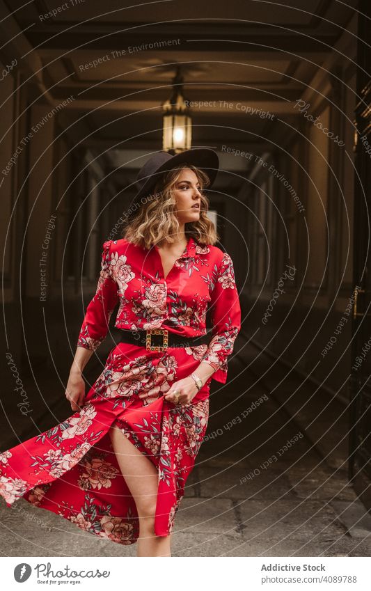 Elegante Frau in alter Passage stehend elegant Durchgang Gebäude Lampe Wegsehen stylisch Stehen Großstadt jung Kleid Hut Outfit trendy Straßenbelag Struktur