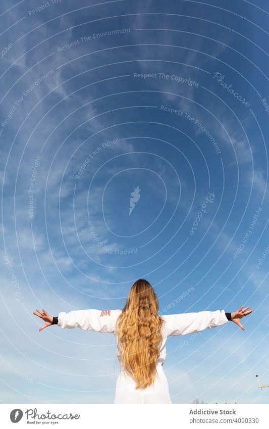 Fröhlicher Teenager hebt die Hände an einem sonnigen Tag Mädchen erreichend Hände hoch Lächeln Himmel Wolken tagsüber Glück aufgeregt heiter Freude Lifestyle