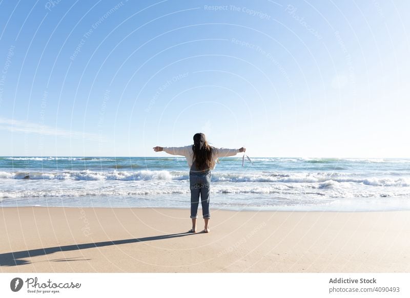 Lächelndes Mädchen hält Bänder am Strand MEER Accessoire Barfuß Sand zeigend Wellen sonnig Tourismus Urlaub tagsüber Kind Teenager Meer Wasser demonstrierend