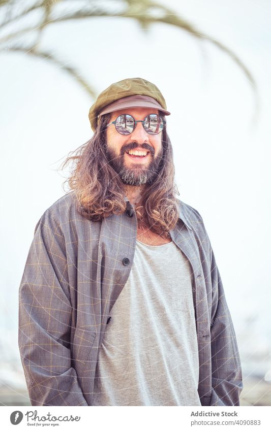 stilvollen bärtigen Mann mit langen Haaren zu Fuß auf der Straße mit Sonnenbrille trendy Schnurrbart Porträt Typ Blick Behaarung cool stylisch gutaussehend