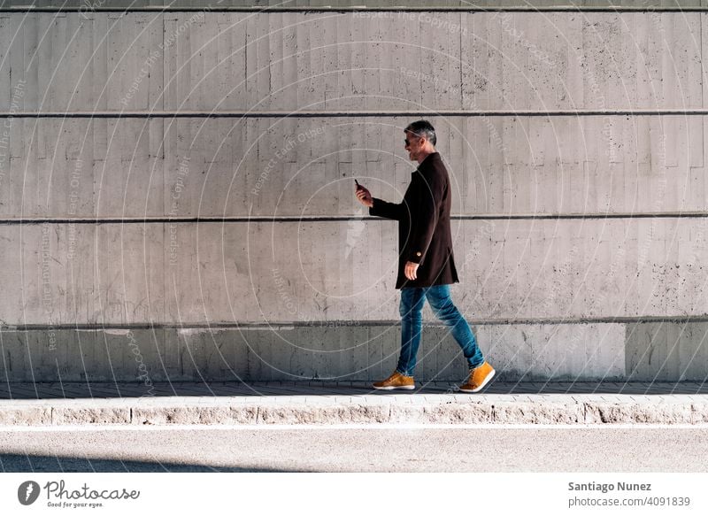 Geschäftsmann, der sein Smartphone auf der Straße benutzt. Mann Person Lifestyle Menschen mittleres Alter gutaussehend Senior im Freien Kaukasier Großstadt