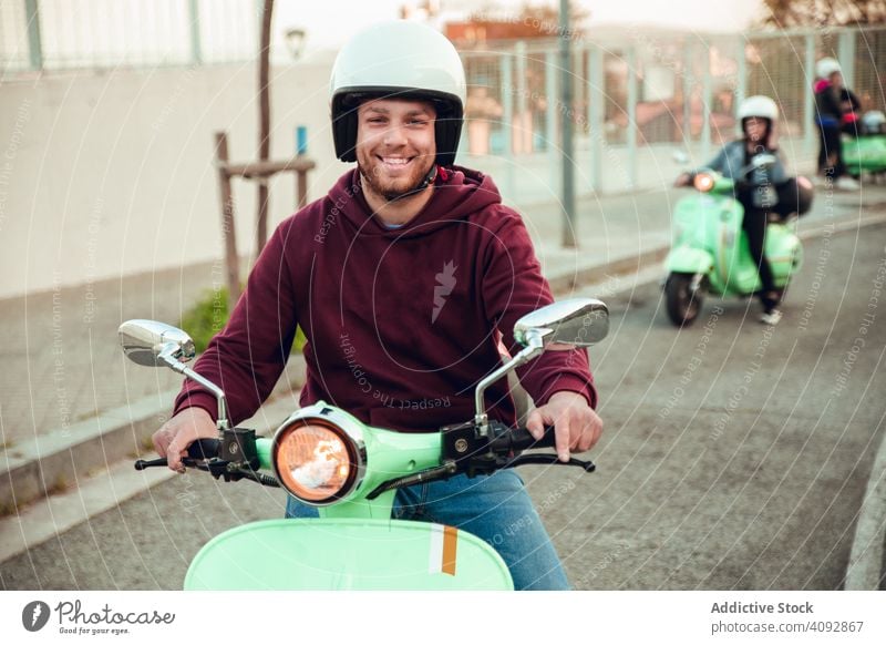 Mann im Motorrad schaut in die Kamera Schutzhelm in die Kamera schauen gutaussehend Tretroller Fahrrad Aktivität Freizeit Straße heiter Abenteuer reisen