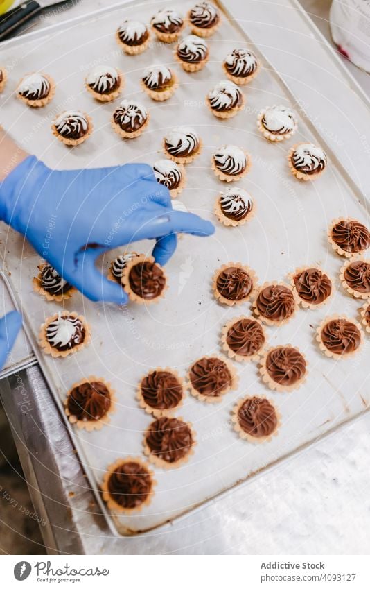 Anonymer Bäcker beim Dekorieren kleiner Kuchen Konditor Bäckerei Gebäck Arbeit Qualität Lebensmittel traditionell Mann Vorbereitung Inszenierung