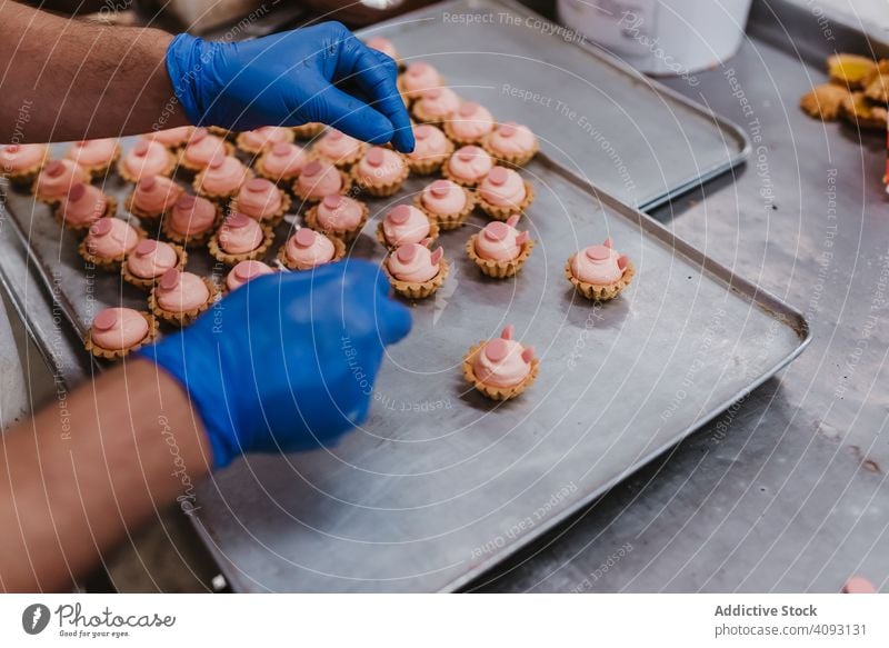 Anonymer Bäcker beim Dekorieren kleiner Kuchen Konditor Bäckerei Gebäck Arbeit Qualität Lebensmittel traditionell Mann Vorbereitung Inszenierung