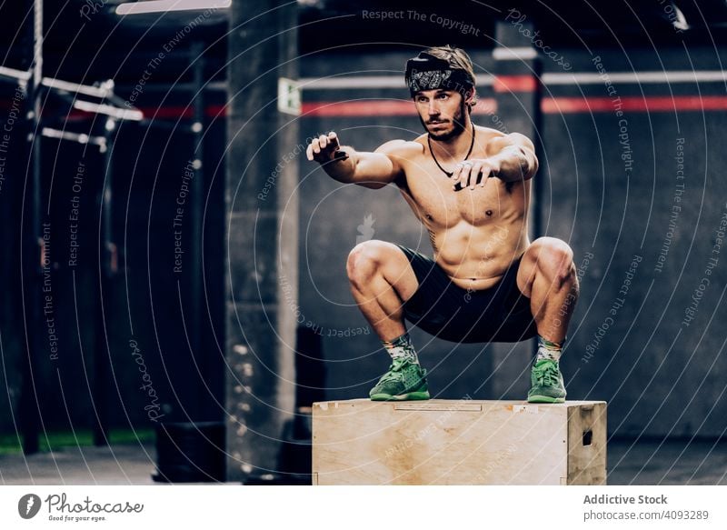 Athletischer Mann springt auf einen Kasten, um seine Ausdauer im Fitnessstudio zu verbessern Trainerin Training muskulös springend Übung sportlich Klient