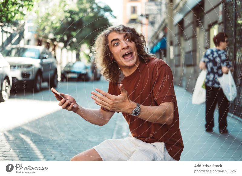 Mann am Mobiltelefon auf der Straße reden Telefon amüsiert lässig Longboard Lachen gestikulieren heiter benutzend sprechen Smartphone sonnig Baluster