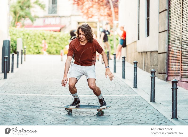 Selbstbewusster Mann fährt mit seinem Longboard über eine Straße in der Stadt Mitfahrgelegenheit Großstadt urban Freestyle Trick fokussiert lässig cool