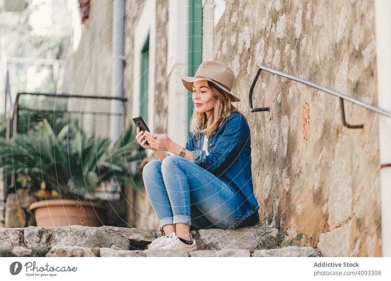 Frau mit Smartphone sitzt auf Steinstufen einer Treppe Glück schön sprechend attraktiv charmant Erholung Straße selbstbewusst Model Mitteilung nachdenklich