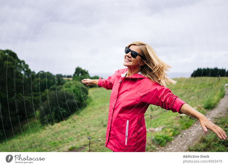 Fröhliche Frau genießt die Landschaft und streckt die Hände aus friedlich Feld genießend strecken Wald Natur grün Erholung lässig Herbst Saison Dame Pflanze