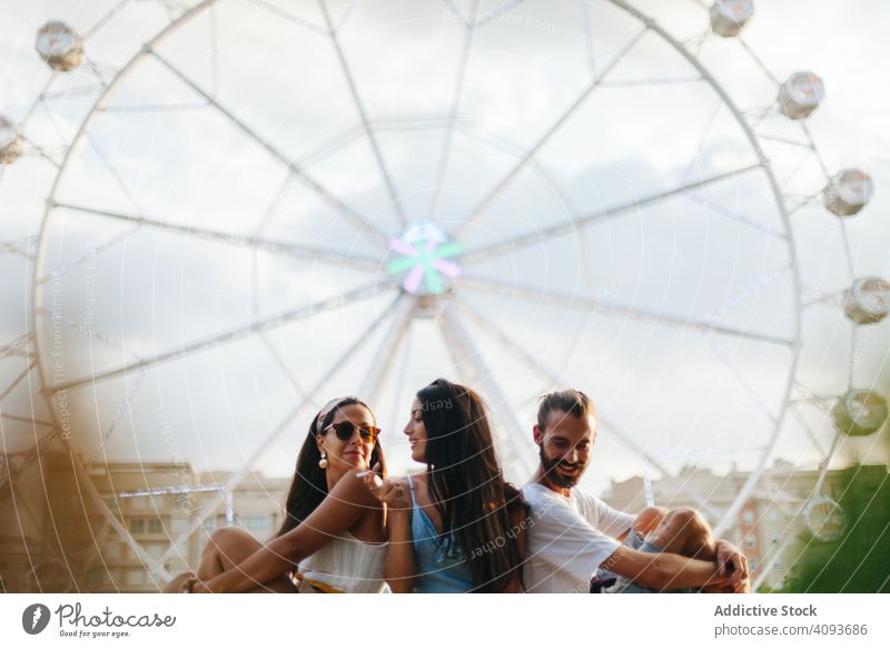 Friedliche Freunde entspannen sich und sitzen neben dem Riesenrad auf dem Rummelplatz sich[Akk] entspannen Messegelände träumen ruhen Inspiration friedlich