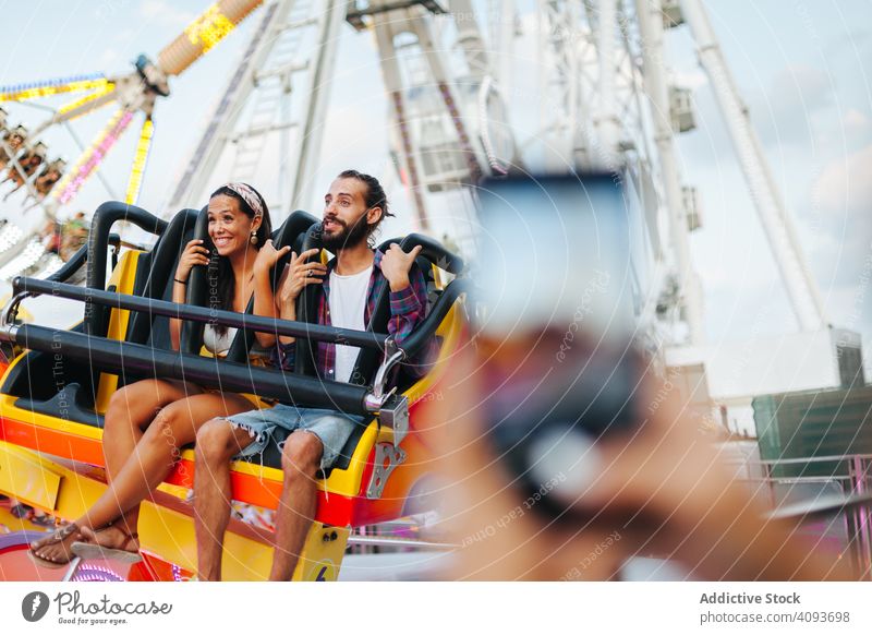 Aufnahme eines aufgeregten Paares auf einem Karussell im Vergnügungspark Vergnügen Park Mitfahrgelegenheit Entertainment fotografierend freudig Glück lässig