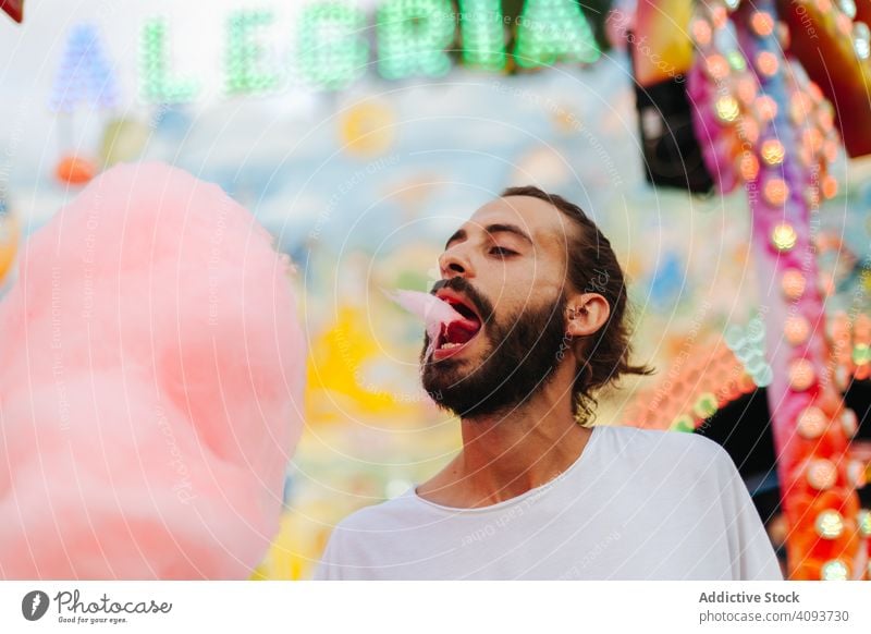 Zufriedener Mann genießt Zuckerwatte auf Kirmes Jahrmarkt essen genießen Spaß Hipster Vergnügen Park erfreut Inhalt Glück bärtig stehen Erwachsener Freude bunt