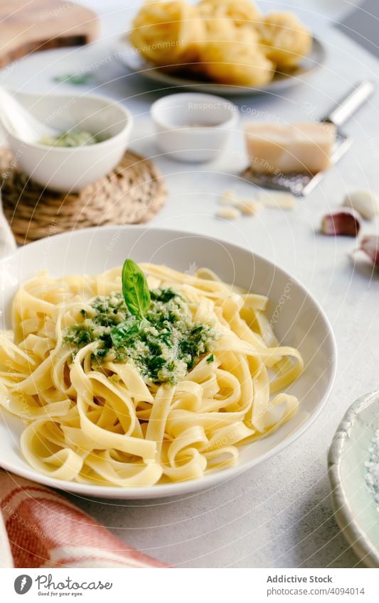 Servierter Teller mit Pesto-Nudeln neben einer Schüssel mit Sauce auf dem Tisch Spätzle Saucen Küche frisch gekocht weiß Knoblauch Erdöl Basilikum Tagliatelle