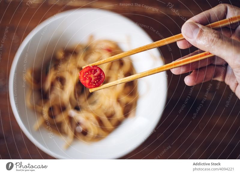 Gesichtslose Person isst Abendessen mit Stäbchen Essstäbchen Kirsche Tomate Nudeln Lebensmittel Mahlzeit Küche Speise Krabbe Asiatische Küche Meeresfrüchte