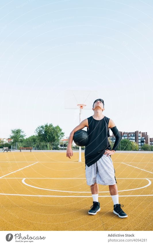 Junger Mann spielt auf gelbem Basketballfeld im Freien. Athlet Konkurrenz Sportgerät Erwachsener Erholung Aktion Ball Porträt aktiv Aktivität Asphalt sportlich