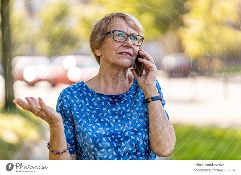 Gestresste ältere Frau, die im Freien ein Mobiltelefon benutzt Menschen Senior reif lässig Kaukasier alt Großmutter Rentnerin Großeltern