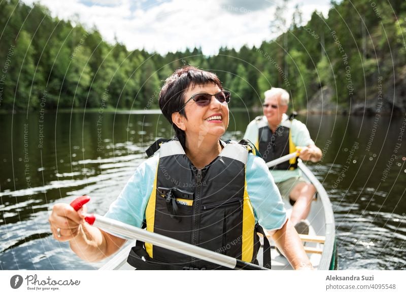 Glückliches reifes Paar in Rettungswesten Kanufahren im Waldsee. Sonniger Sommertag. Touristen, die in Finnland reisen und Abenteuer erleben. aktiv Aktivität