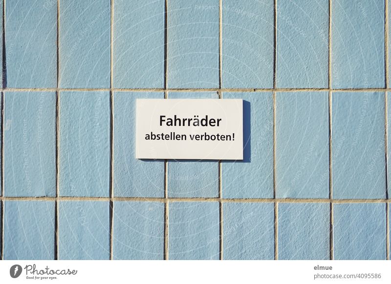 weißes Schild mit der Aufschrift " Fahrräder abstellen verboten ! " an hellblauen Fliesen / Radfahren Fahrrad Fliesen u. Kacheln Geometrie Hinweis Verbot