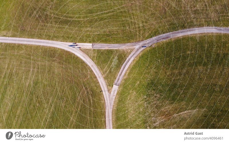 Luftaufnahme mit einer Drohne im Frühling von einer Straßenkreuzung mit einem Radfahrer mit Hunden luftaufnahme drohnenfoto straße feldwege straßenkreuzung