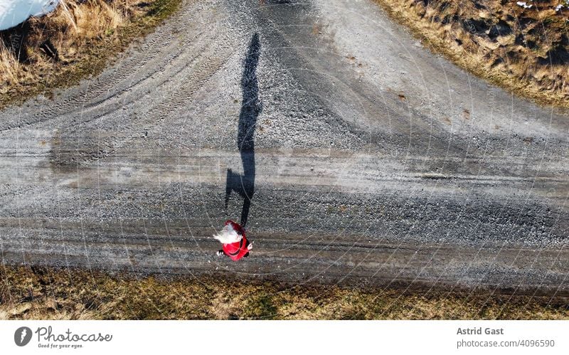 Luftaufnahme mit einer Drohne von einer Joggerin auf einer Straße mit Schatten luftaufnahme drohnenfoto frühling sport joggen frau joggerin laufen rennen straße