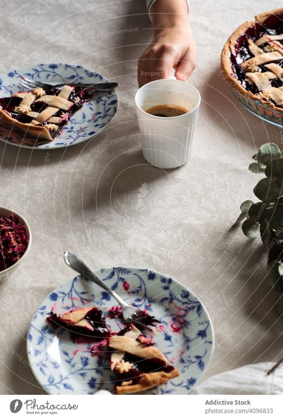 Gesichtslose Person genießt Kaffee mit selbstgebackenem Kuchen Pasteten lecker selbstgemacht Beeren serviert essen trinken genießen vorbereitet gekocht süß